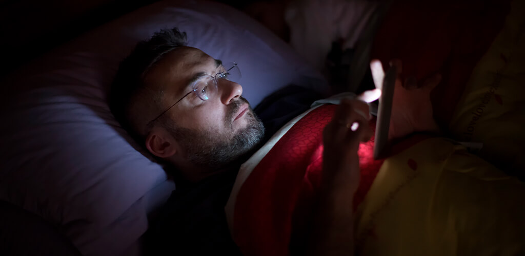 A man using his phone in bed.