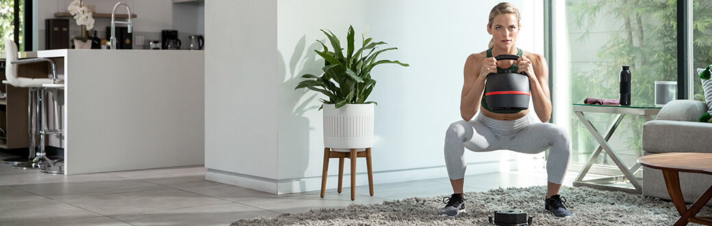 A woman performing a squat with a kettlebell.