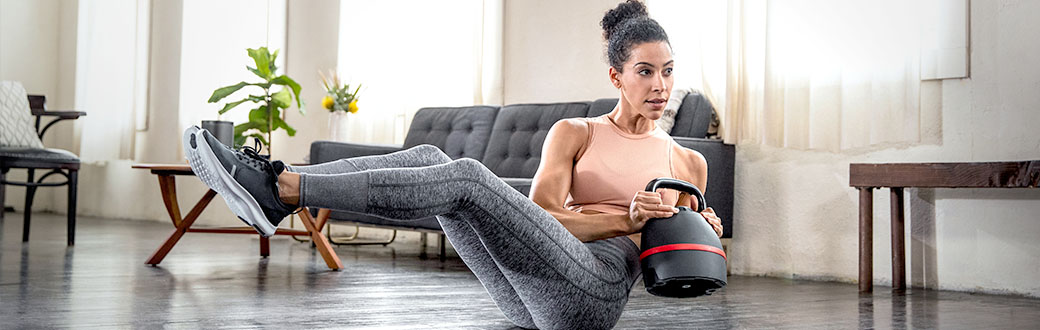 A woman performing a seated twist using a kettlebell.