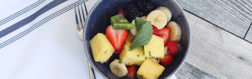 A bowl of fruit salad with lemon mint dressing.