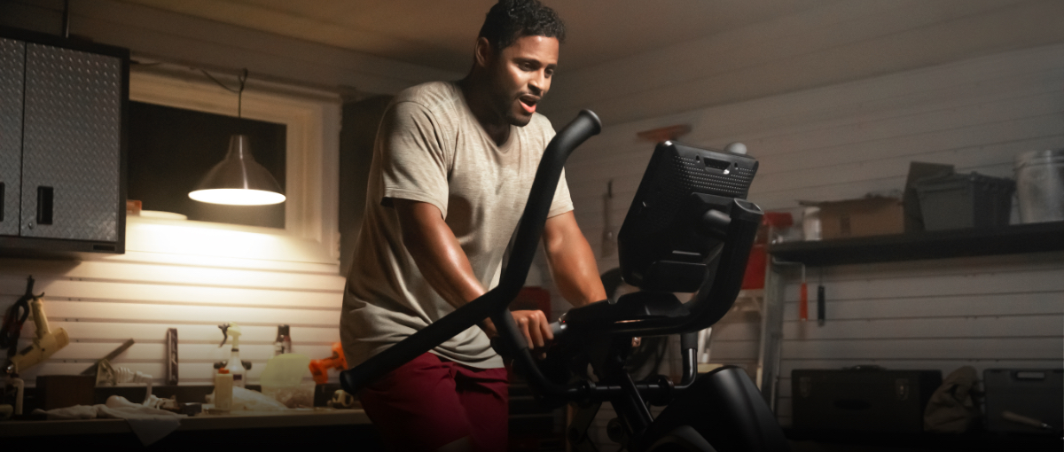 A man using a Max Trainer compact elliptical in his cramped garage.