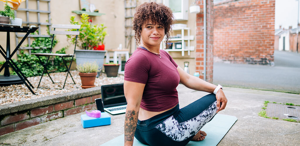 A woman in her backyard stretching.