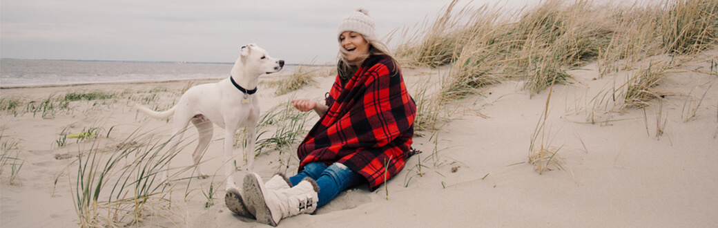 A woman on the beach with her dog.