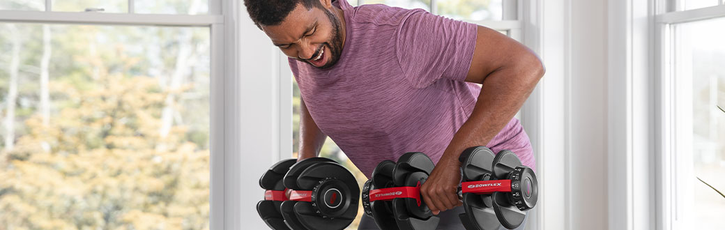 A man performing bent over rows with adjustable dumbbells.