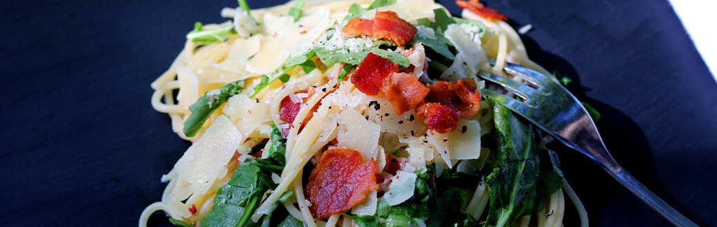 bacon arugula pasta on a plate.