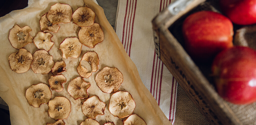 Baked apple slices on a plate surrounding a bowl of yogurt dip.