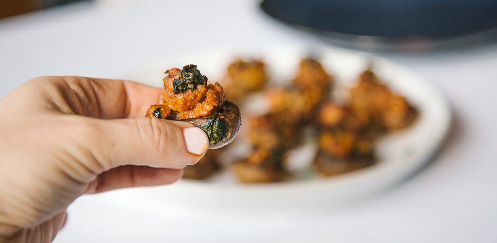 A hand holding a stuffed mushroom.