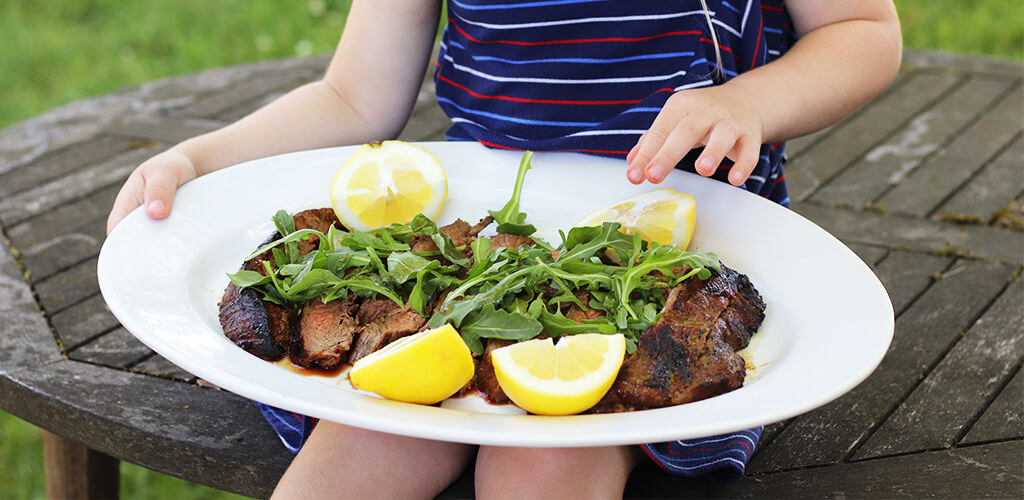 flank steak with arugula and lemon on a plate