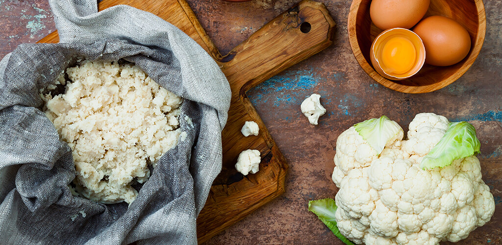 Riced cauliflower, cauliflower, and eggs on a table.