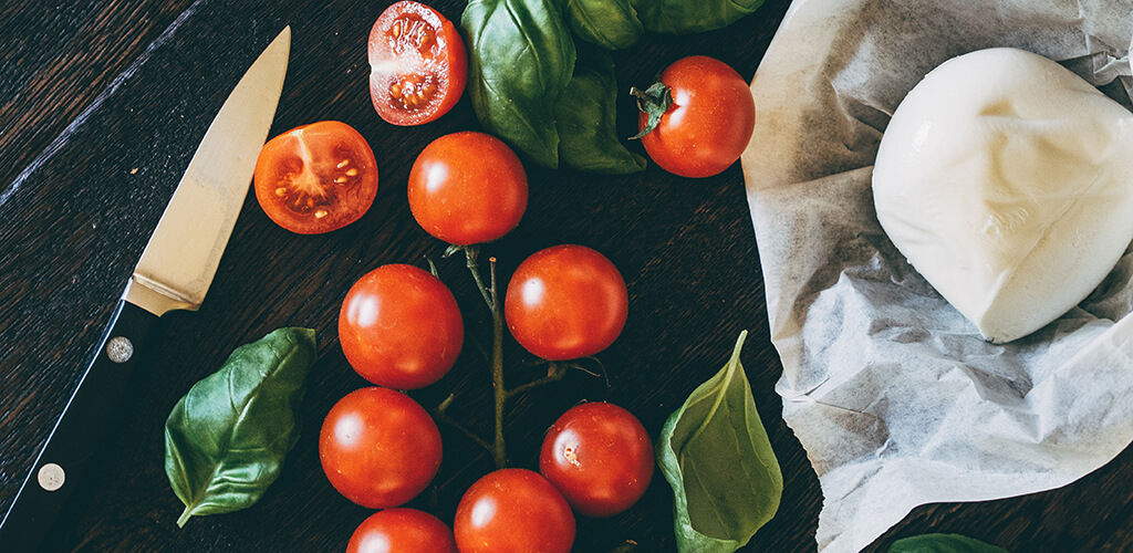 basil, tomatoes, and mozzarella cheese on a table.