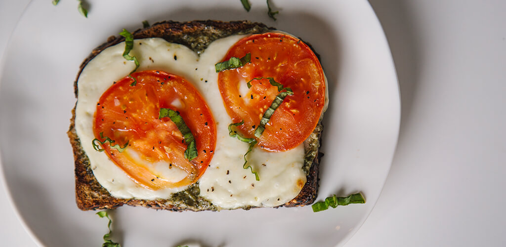 Tomato, Pesto, And Fresh Mozzarella Open-Faced Grilled Cheese sandwich on a plate.