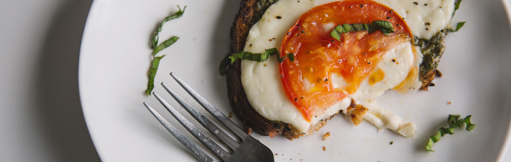 Open-faced Tomato, Pesto, And Fresh Mozzarella Grilled Cheese on a plate.