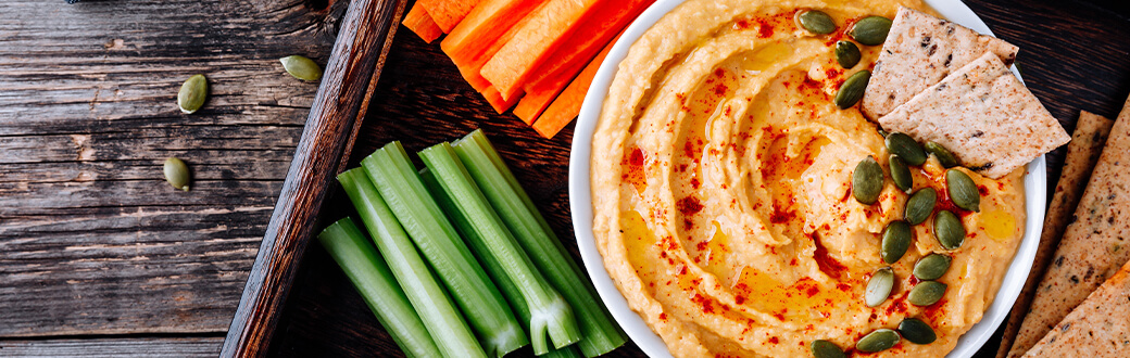 hummus in a bowl next to vegetables.