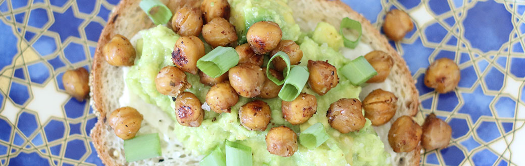 Toasted chickpeas on avocado toast on a plate.