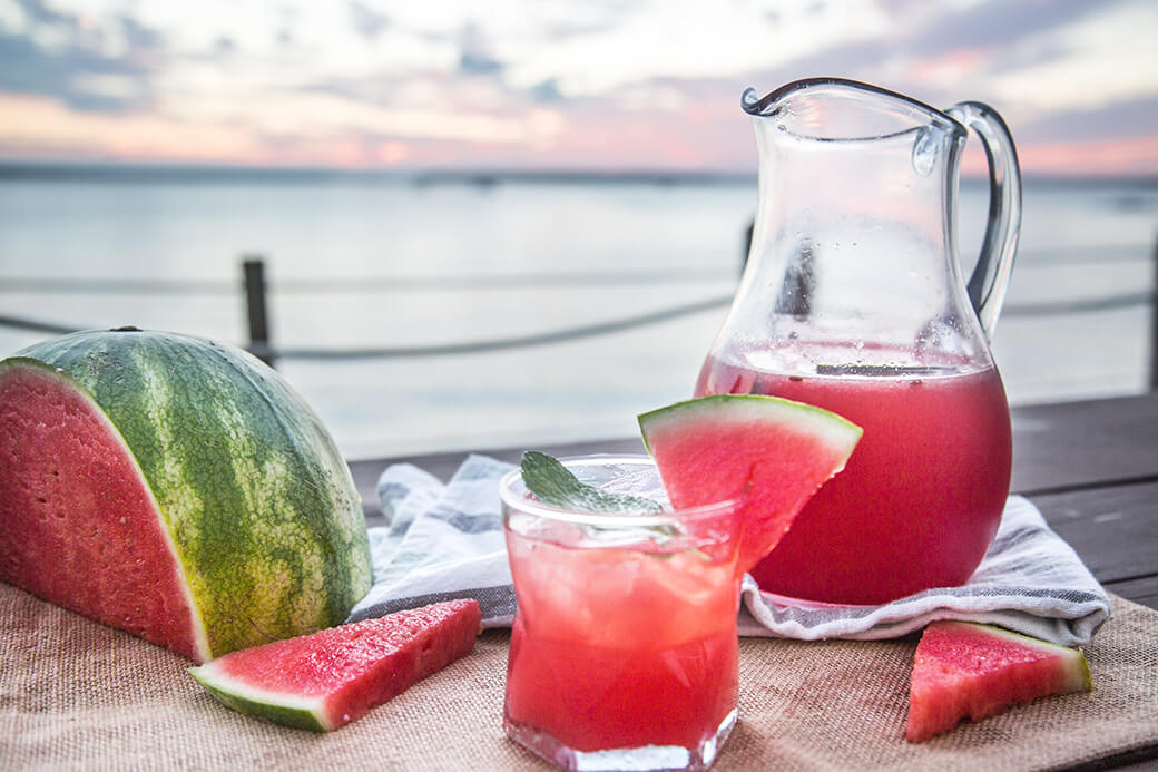 A glass filled with watermelon mojito mocktail. Garnished with mint and watermelon.