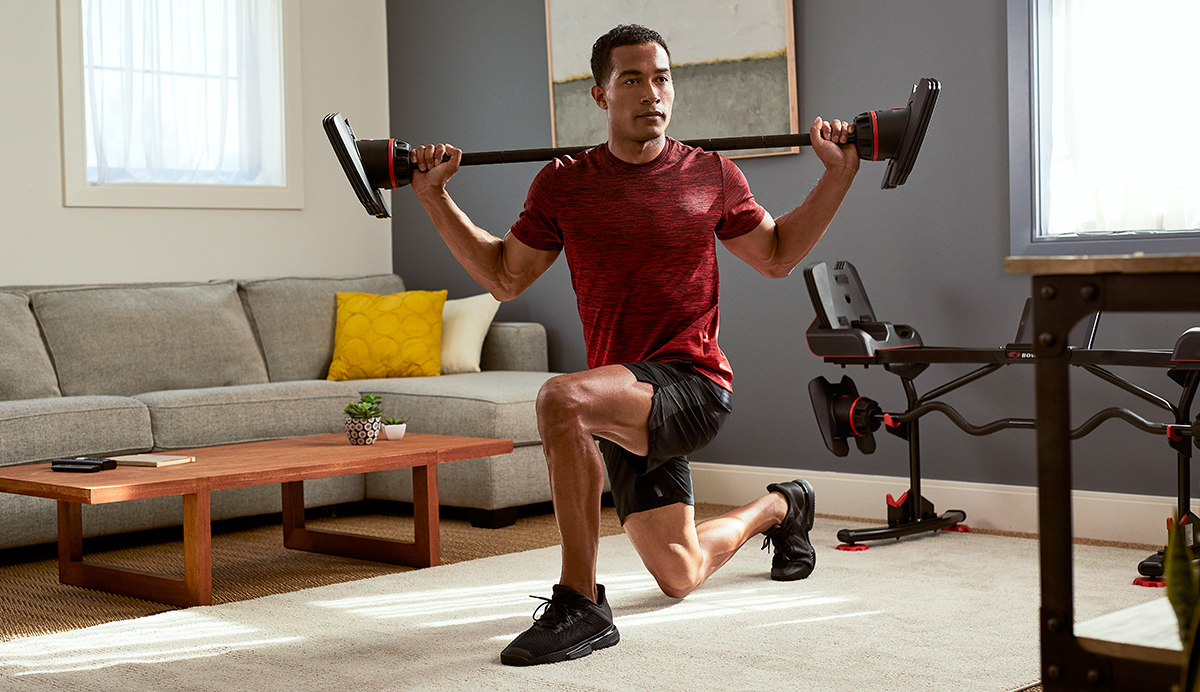 Man doing a barbell lunge in his living room