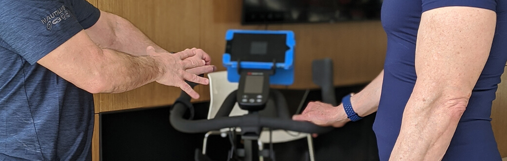 Two people next to a Bowflex C6 Bike.