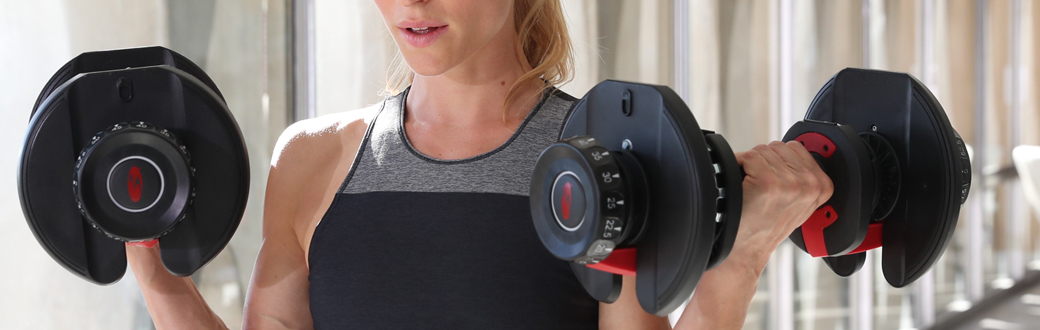 A fit woman using Bowflex SelectTech Dumbbells.