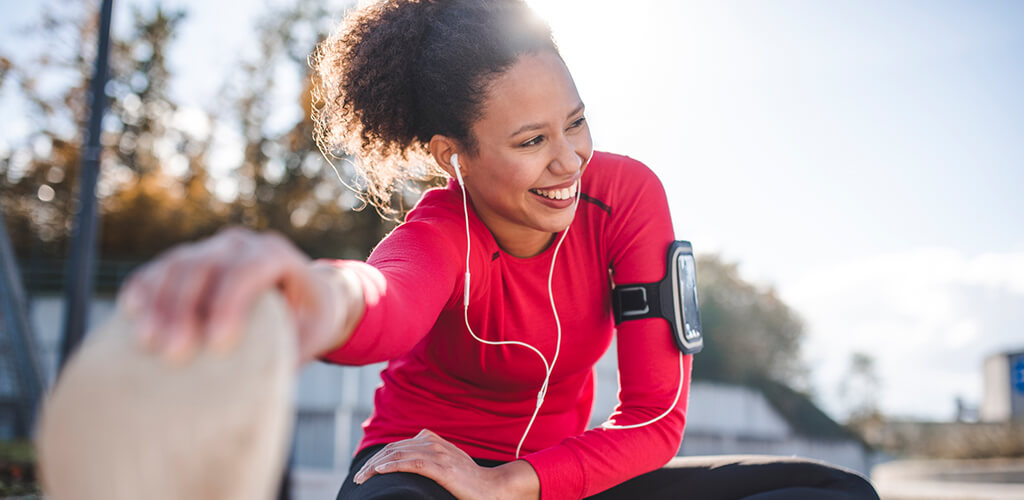 A woman outdoors stretching before a run.